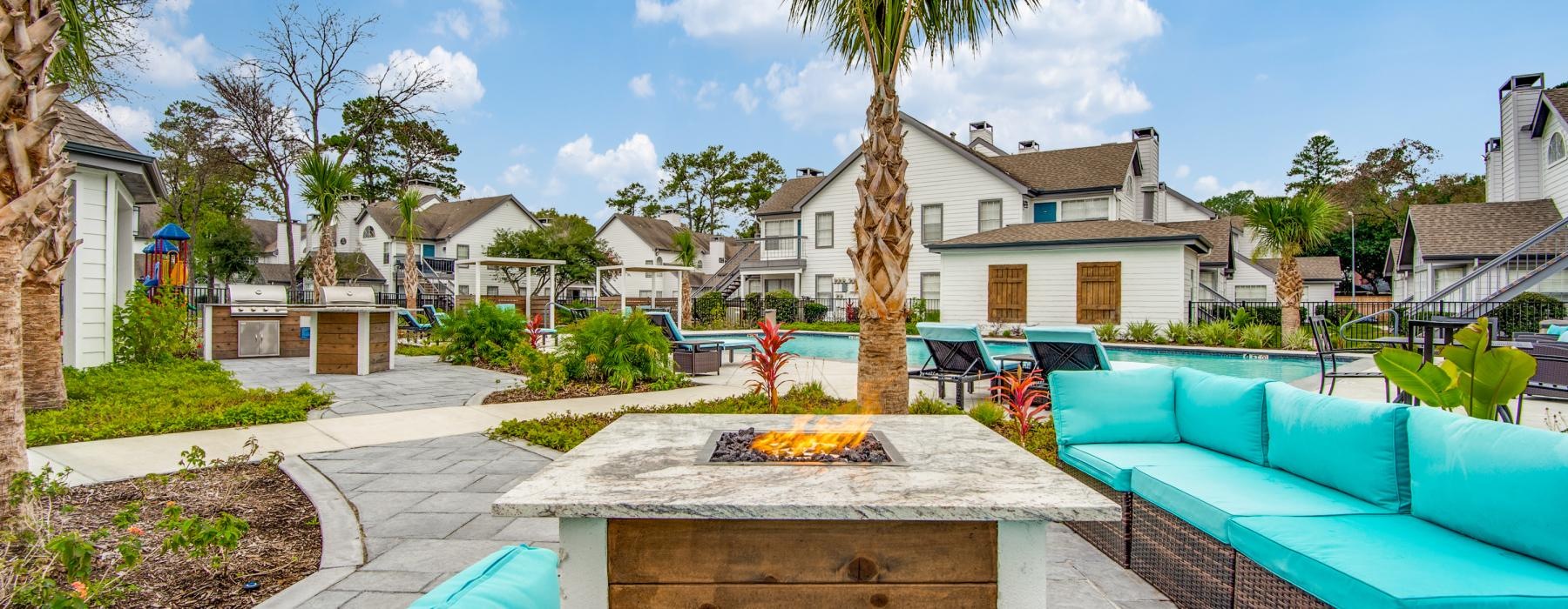 a firepit by the a pool with seating